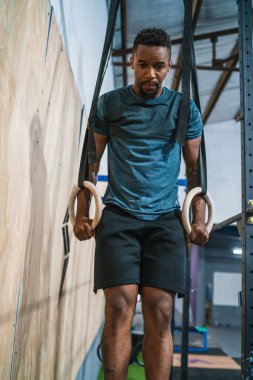 Spor salonunda yüzüklerle kaslarını çalıştıran genç bir sporcunun portresi. Crossfit, spor ve sağlıklı yaşam tarzı konsepti.