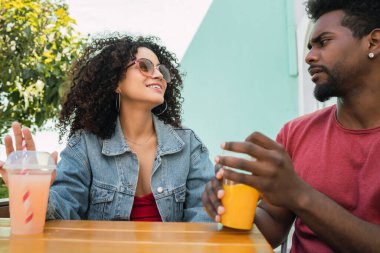 Kafeteryada taze meyve suyu içerken birlikte eğlenen ve eğlenen iki Afro arkadaşın portresi.