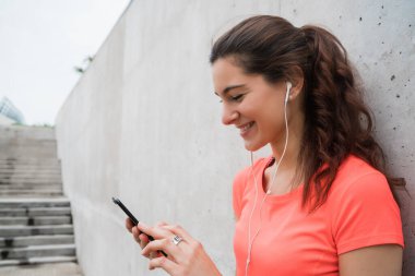 Eğitime ara verdiğinde cep telefonunu kullanan atletik bir kadının portresi. Spor ve sağlık yaşam tarzı.