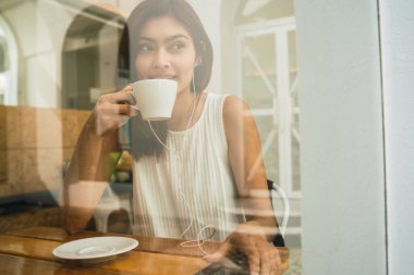 Kafede eğlenen ve bir fincan kahve içen genç Latin kadının portresi. Yaşam tarzı kavramı.