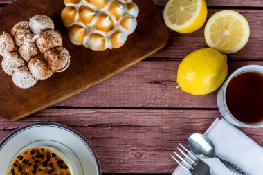 Lezzetli mini çikolataya, limonlu turtaya ve bir fincan çayla tutkulu meyveli keke yakın çekim. Pişirme kavramı.