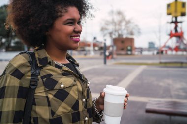 Sokakta elinde bir fincan kahve tutan güzel Afro-Amerikan Latin kadının portresi. Şehir konsepti.