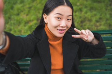 Parktaki bankta otururken selfie çeken güzel bir Asyalı kadının portresi..