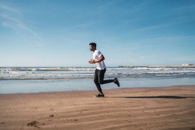 Sahilde koşan atletik bir adamın portresi. Spor, spor ve sağlıklı yaşam tarzı..