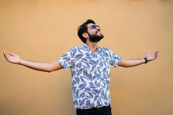 Genç yakışıklı adamın portresi yazdan zevk alıyor ve sarı arka planda yaz kıyafetleri giyiyor.. 