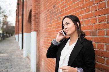 Sokakta telefonda konuşan genç Latin bir kadının portresi. Şehir konsepti.