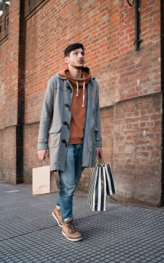 Sokakta yürürken alışveriş torbaları tutan yakışıklı bir adamın portresi. Kentsel, alışveriş konsepti.