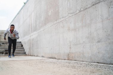 Gri arka planda koşan atletik bir adamın portresi. Spor ve sağlıklı yaşam tarzı.