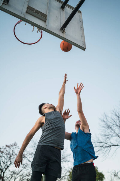 Portrait of two young friends playing basketball and having fun on court outdoors. Sports concept.