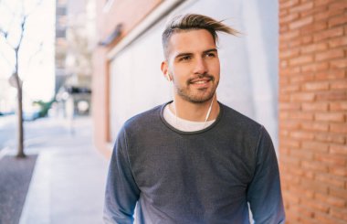 Sokakta kulaklıkla müzik dinleyen yakışıklı bir adamın portresi. Şehir konsepti.