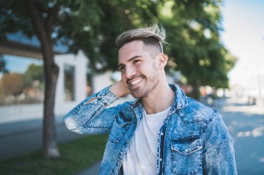 Sıradan kıyafetler giyen ve sokakta yürüyen yakışıklı bir adamın portresi. Şehir konsepti.