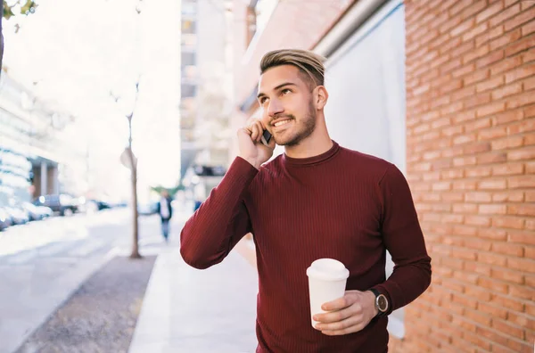 Портрет Молодого Красивого Мужчины Разговаривающего Телефону Держа Чашку Кофе Улице — стоковое фото