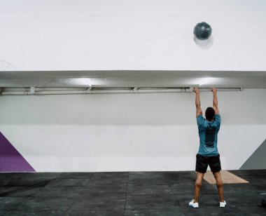Spor salonunda topla egzersiz yapan genç çapraz formda bir sporcunun portresi. Crossfit, spor ve sağlıklı yaşam tarzı konsepti.