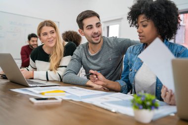 Genç yaratıcı tasarımcılar bir projede çalışıyor ve işyerindeki yeni düzen gelişimini tartışıyorlar. İş ve takım çalışması kavramı.