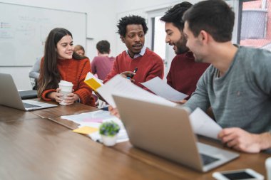 Genç yaratıcı tasarımcılar bir projede çalışıyor ve işyerindeki yeni düzen gelişimini tartışıyorlar. İş konsepti.