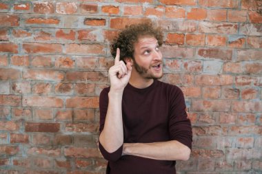 Sokaktaki tuğla duvara karşı bir fikri olan beyaz bir gencin portresi. Şehir konsepti.