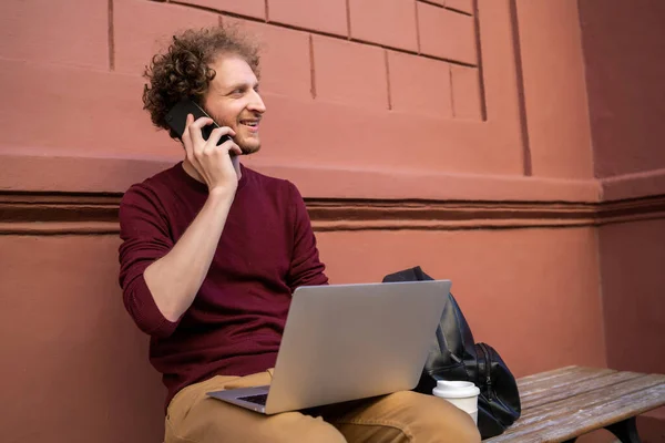 Πορτρέτο Του Νεαρού Που Μιλάει Στο Τηλέφωνο Και Χρησιμοποιεί Laptop — Φωτογραφία Αρχείου
