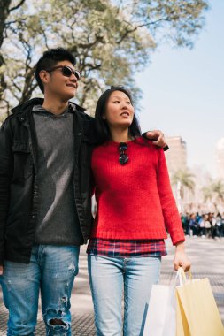 Alışveriş yaptıktan sonra şehirde yürüyen Asyalı genç bir çiftin portresi. Dükkan konsepti.