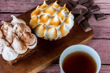 Lezzetli mini çikolatalı keke ve bir fincan çayla limonlu pastaya yakın çekim.