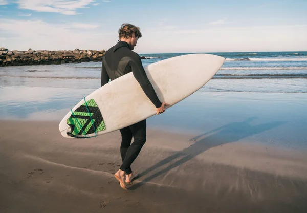 Der Junge Surfer Steigt Mit Seinem Surfbrett Einem Schwarzen Surfanzug — Stockfoto
