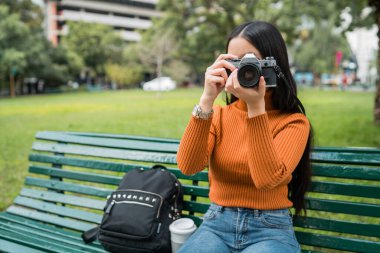 Parkta profesyonel dijital kamera kullanan Asyalı genç bir kadının portresi. Fotoğraf konsepti.