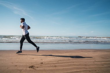 Sahilde koşan atletik bir adamın portresi. Spor, spor ve sağlıklı yaşam tarzı..