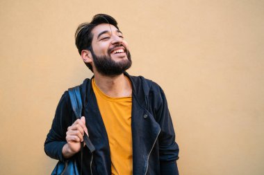 Sırt çantalı, sarı arka planda çekici genç adam portresi. Şehir konsepti.