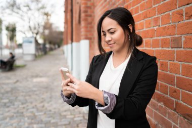 Sokakta cep telefonunu kullanan güzel bir kadının portresi. Kentsel ve iletişim konsepti.