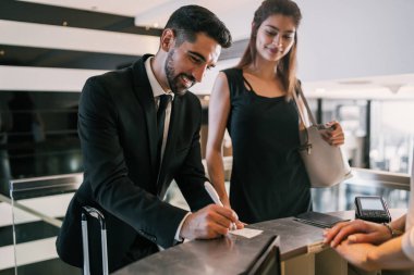 İki genç iş adamının portresi otel resepsiyonunda kayıt yaptırıyor. İş seyahati kavramı.