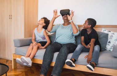 Evde VR gözlükleriyle oynayan Afrikalı Amerikalı büyükanne ve torunların portresi. Aile ve teknoloji kavramı.