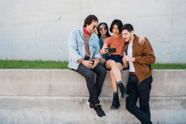 Birlikte eğlenen ve cep telefonuyla selfie çekerken eğlenen bir grup arkadaşın portresi. Yaşam tarzı ve arkadaşlık kavramı.