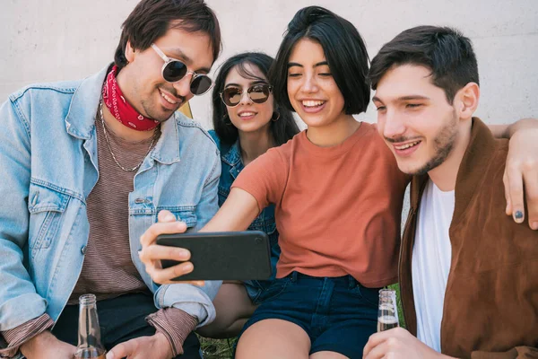 Birlikte eğlenen ve cep telefonuyla selfie çekerken eğlenen bir grup arkadaşın portresi. Yaşam tarzı ve arkadaşlık kavramı.
