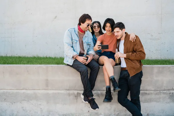 Birlikte eğlenen ve cep telefonuyla selfie çekerken eğlenen bir grup arkadaşın portresi. Yaşam tarzı ve arkadaşlık kavramı.
