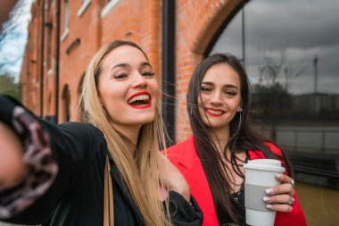 Sokakta selfie çeken iki genç arkadaşın portresi. Yaşam tarzı ve arkadaşlık kavramları.