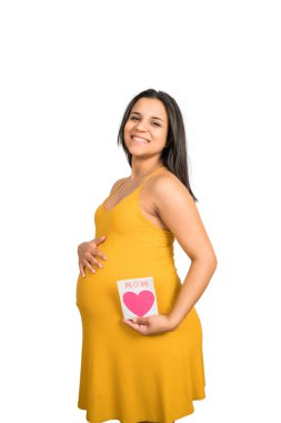 Beyaz arka planda tebrik kartı tutan hamile kadının yakın çekimi. Hamilelik, yeni anne ve annelik kavramı.