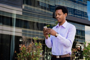 Sokakta cep telefonunu kullanan genç afro iş adamının portresi. İş konsepti.