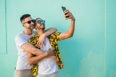 Mutlu eşcinsel çiftin portresi. Birlikte zaman geçirip cep telefonuyla selfie çekiyorlar. Lgbt ve Aşk Konsepti.