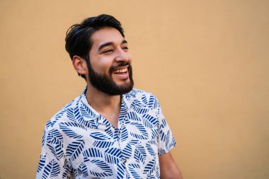 Genç yakışıklı adamın portresi yazdan zevk alıyor ve sarı arka planda yaz kıyafetleri giyiyor.. 