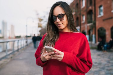 Sokakta cep telefonunu kullanan güzel bir kadının portresi. Kentsel ve iletişim konsepti.