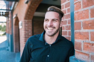 Sokakta gülen ve yürüyen genç yakışıklı bir adamın portresi. Şehir konsepti.