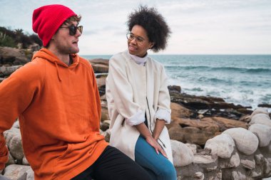 İki genç arkadaşın portresi, arka planda deniz otururken birlikte iyi vakit geçirip sohbet ediyorlar..