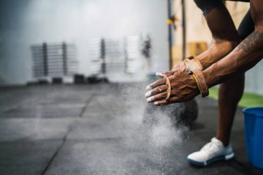 Portrait of fitness young man rubbing hands with chalk magnesium powder, preparing for workout in crossfit gym. Sport and healthy lifestyle concept. clipart