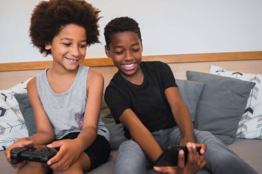 Evde cep telefonuyla selfie çeken iki Afro-Amerikan kardeşin portresi. Yaşam tarzı ve teknoloji kavramı.