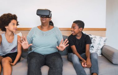 Evde VR gözlükleriyle oynayan Afrikalı Amerikalı büyükanne ve torunların portresi. Aile ve teknoloji kavramı.