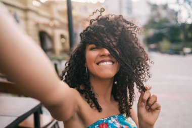 Sokakta selfie çeken Afro-Amerikan genç bir kadının portresi. Hayatın tadını çıkarıyorum. Yaşam tarzı kavramı.