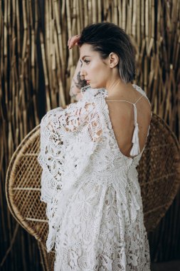 boho tarzında beyaz elbise giyen stüdyoda kadının yan görünümü bambu arka plan karşı duran 