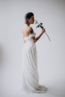 beyaz elbise giyen ve çiçek kokulu açık arka plan üzerinde duran gelinin yan görünümü 