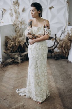  brunette in vintage white dress standing around studio decorations  and looking away 