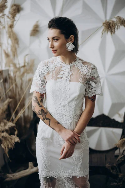 stylish tattooed lady posing in white dress, studio shot