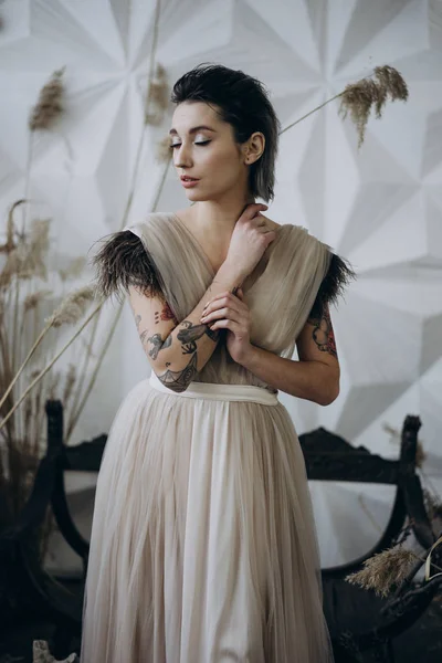portrait of tattooed lady with closed eyes posing in the studio wearing dress